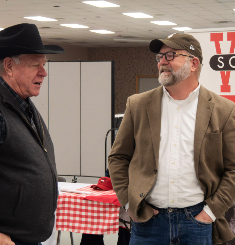 Two men talk beside a red-and-white checkered table during the Southeast Wyoming Beef Symposium.