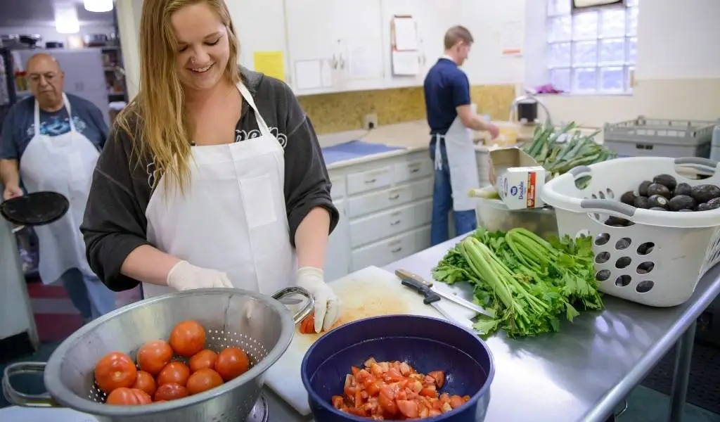 woman smiling in kitchen cutting up tomatoes