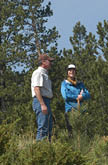 Man and women in conversation in front of ponderosa pine trees on clear  sunny day 