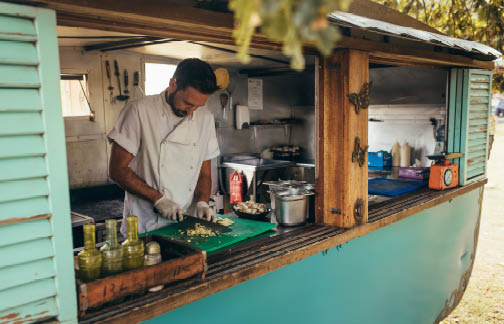 Man wearing gloves chopping vegetables inside a food truck