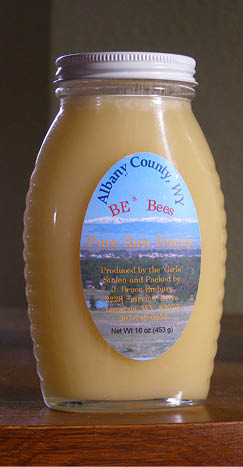 Local honey packaged in clear glass bottle with white metal lid