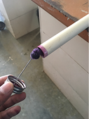 Applying purple primer to one end of a PVC pipe 