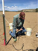 Producter installing PVC pipes with sensors in dirt field 