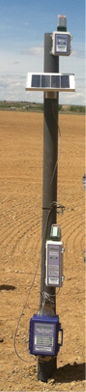 Tall pole in a field with wireless mesh data monitoring system sensor node  data logger  and cell gateway battery pack powered by solar panel attached 