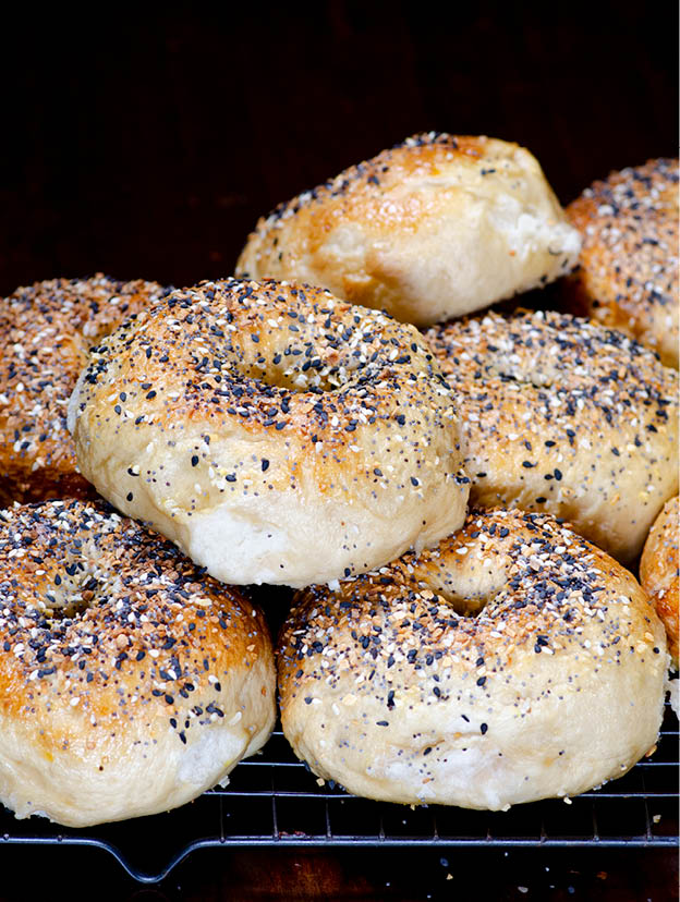 A stack of bagels with various seasonings. 
