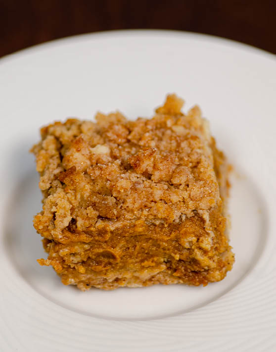 A square piece of a pumpkin pie crumb topped bar placed on a white plate. 