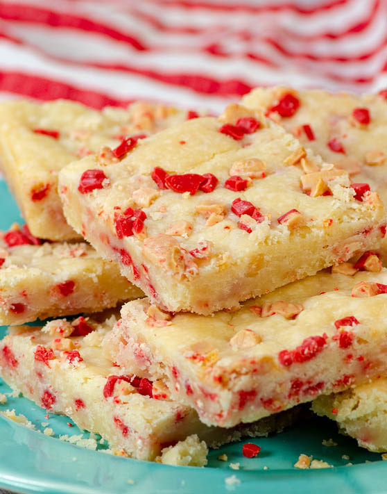 A blue plate with peppermint crucnch shortbread bars with red and white stripes in the background. 
