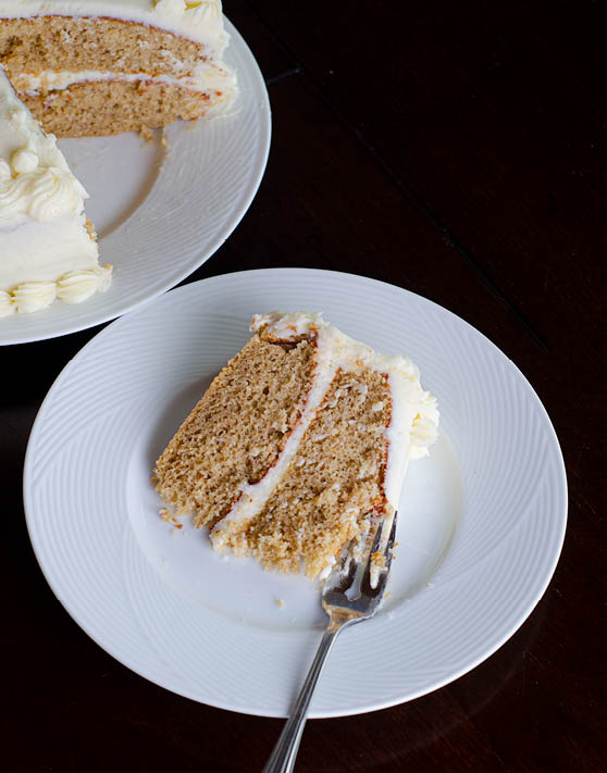 A slice of egg yolk spice cake placed on a white plate, with the cake in the background. 