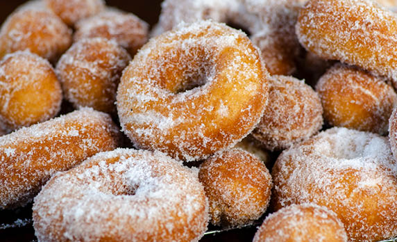 A pile of cake doughnuts covered in sugar. 