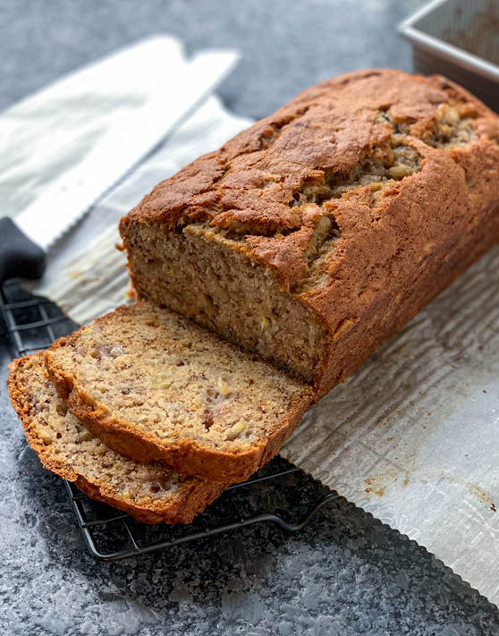 A loaf of banana bread with two slices cut out of it. 
