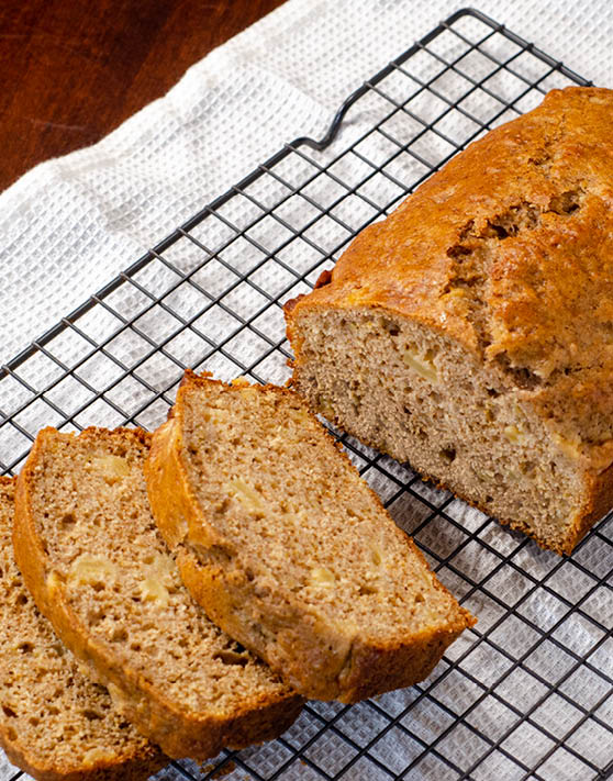 A loaf of pear spice bread with three sliced pieces on top of a cooling rack. 