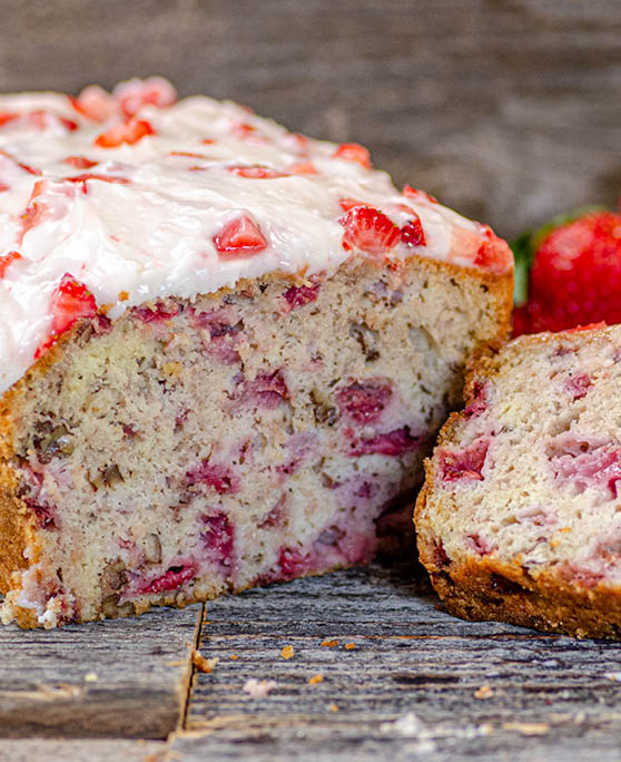 A loaf of strawberry bread with a slice placed to the right of the loaf. 