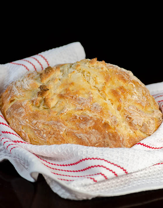 White soda bread wrapped in a white and red towel. 