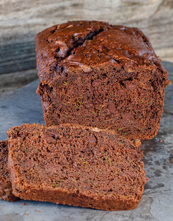 A loaf of chocolate zucchini bread with two slices cut out of it. 