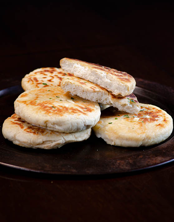 Garlic naan placed on a brown plate. 
