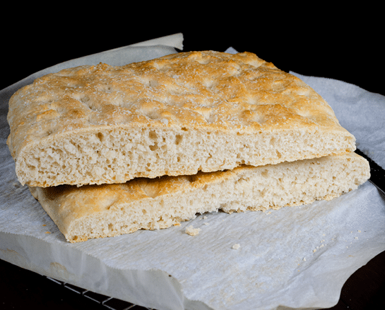 Two slices of Italian focaccia bread placed on a slab of white rock. 