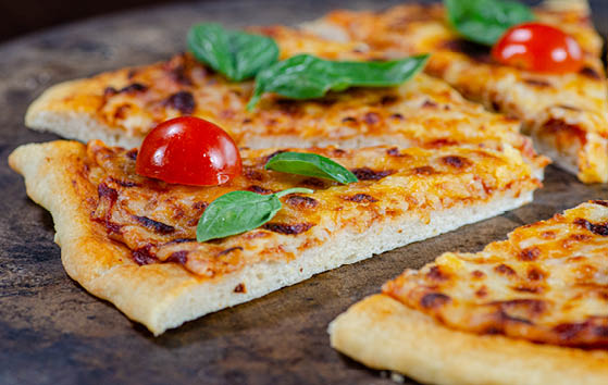 Thin crust pizza topped with fresh basil and halved cherry tomatoes.