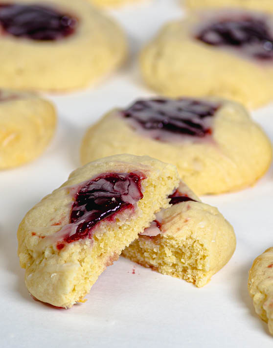 A close up of almond thumbprint sugar cookies, with a red glaze in the center. 