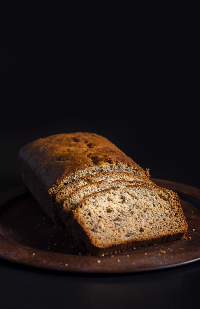 Banana bread slices and loaf sitting on a rusty-looking round platter