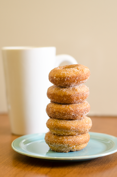 Stack of 5 doughnuts on a blue plate  Tall white coffee mug in the background 