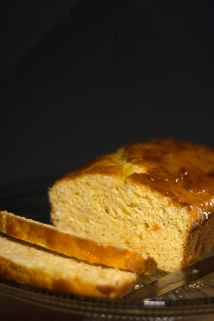 Slices and loaf of orange bread on a glass cake pedestal 