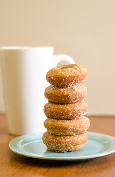 Stack of 5 doughnuts on a blue plate  Tall white coffee mug in the background 
