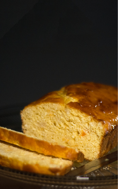 Slices and loaf of orange bread on a glass cake pedestal 