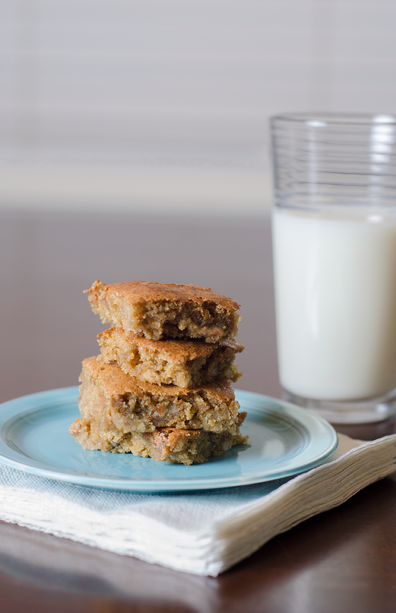 4 bar cookies stacked on a vintage aqua blue Fiestaware plate  The plate is sitting on a stack of napkins  A glass of milk is in the background 