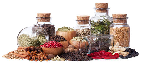 herbs and spices in glass bottles with cork stoppers and wood bowls