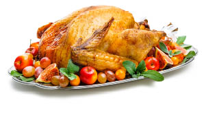 Roast turkey on silver platter  garnished with sage leaves  apples  grapes and figs 