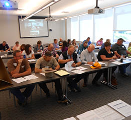 People sitting at tables listening to disaster briefing 