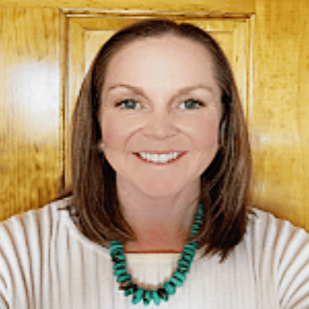 Stephanie Styvar: A headshot of Stephanie Styvar, smiling warmly while wearing a turquoise necklace, posed against a wooden background.