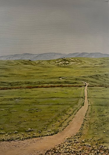A dirt path cuts through a vast green prairie, curving gently toward distant hills and a muted horizon. The open space and subtle tones reflect the quiet expanse of Wyoming’s grasslands.