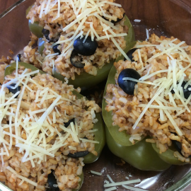 Three cooked stuffed peppers in glass baking dish