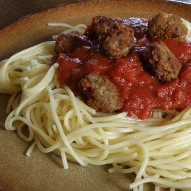 spaghetti with sauce and pile of meatballs on brown plate