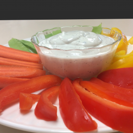 dip in clear bowl surrounded by sliced vegetables