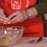 hands pulling meat from cooked chicken bones