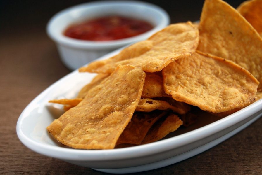 baked chips on white plate with salsa out of focus in background