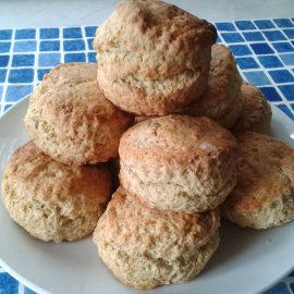 cooked biscuits piled high on white plate with blue tile background