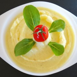 white cinderella bowl with mashed potatoes, garnished with basil and cherry tomato