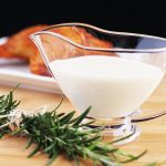 white gravy in dish with rosemary sprig