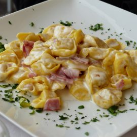 cheese sauce over shell pasta on white plate