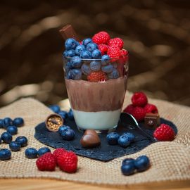 pudding in glass cup filled with berries spilling out of cup