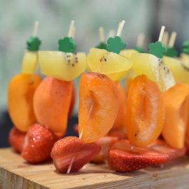 line of colorful fruits on green skewers