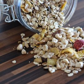 oatmeal and dried berries spilling from glass container with lid