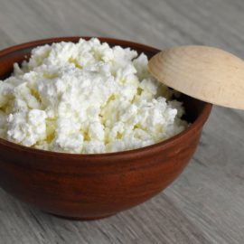 cottage cheese in dark brown bowl with wooden spoon