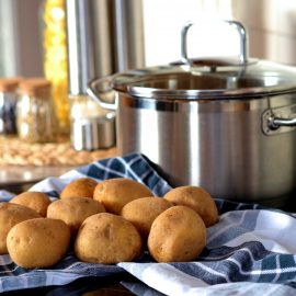 brown potatoes on blue dish towel next to large cooking pot