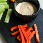 dip in black cup with sliced vegetables on black plate