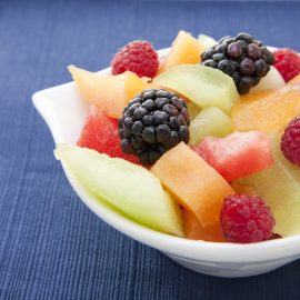 chopped melon and berries in white bowl