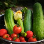 fresh zucchini and tomatoes in metal colander